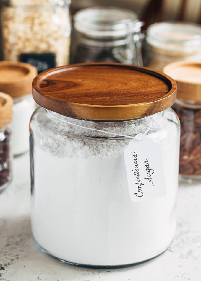 glass pantry storage containers with powdered sugar and dry goods