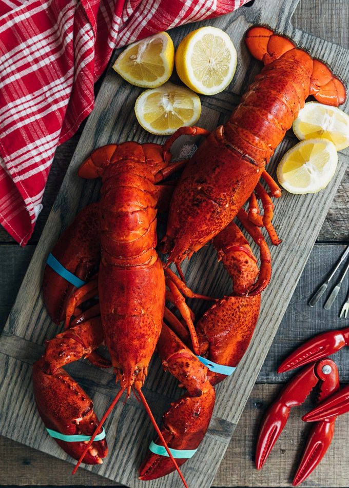 steamed lobsters on a wood board with lemon wedges