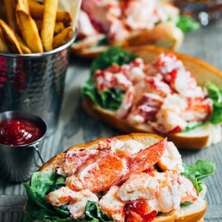 maine lobster rolls on a wood board with french fries