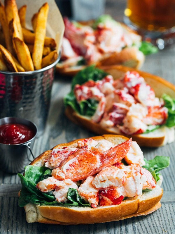 maine lobster rolls on a wood board with french fries