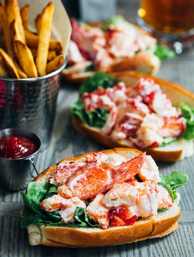 maine lobster rolls on a wood board with french fries
