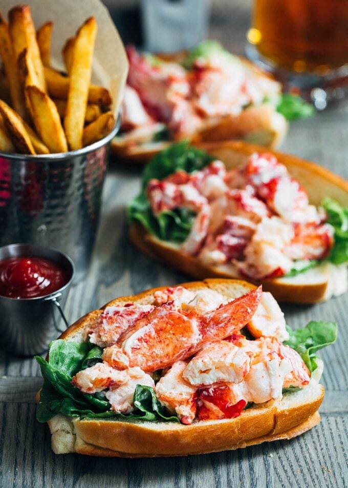 maine lobster rolls on a wood board with french fries