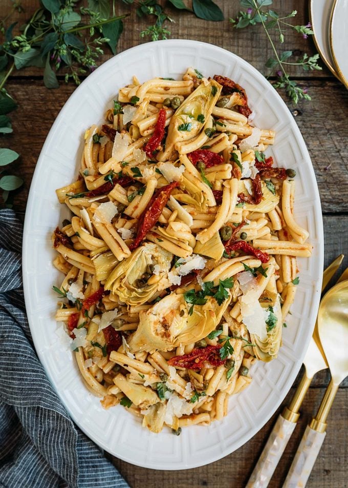 artichoke pasta salad recipe with sun-dried tomato vinaigrette on a white serving platter