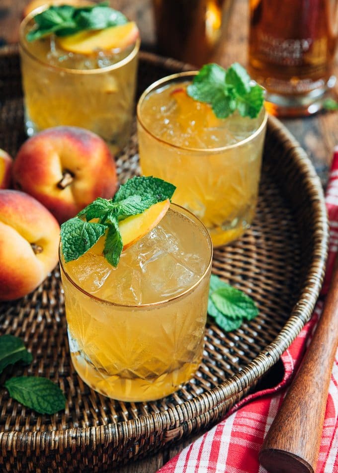 peach bourbon cocktails on a wicker serving tray