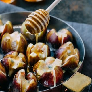 drizzling honey over baked Cambozola stuffed figs with a honey dipper