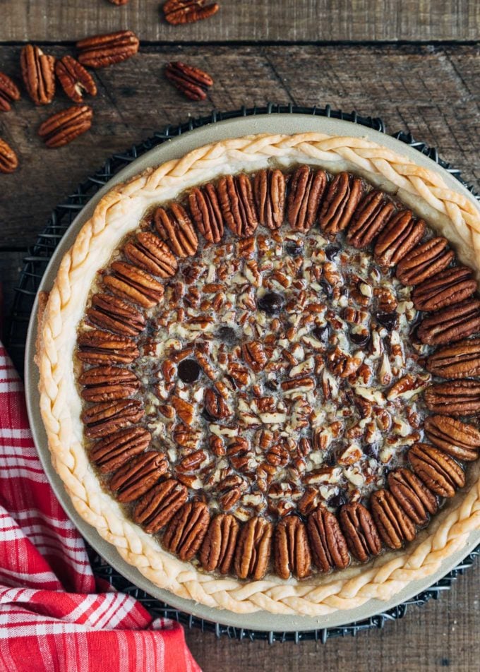 unbaked chocolate pecan pie on a wood board with a red plaid napkin