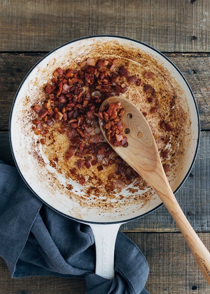 cooked bacon in a white le creuset skillet