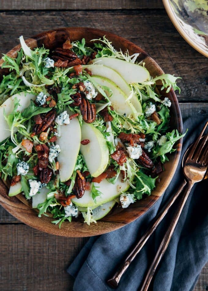 pear salad with blue cheese and warm bacon vinaigrette in a wooden bowl