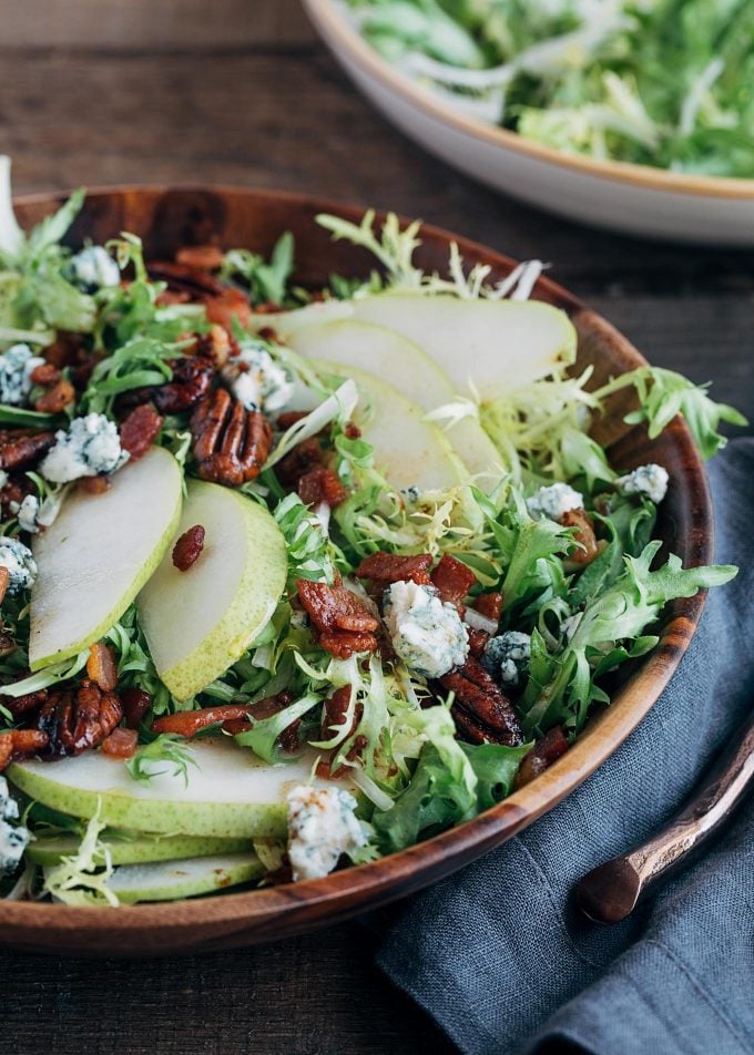 frisee salad with pears and warm maple bacon vinaigrette in a serving bowl