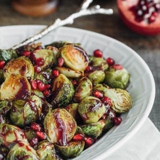 roasted brussels sprouts with pomegranate in a white serving dish