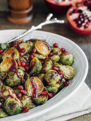 roasted brussels sprouts with pomegranate in a white serving dish