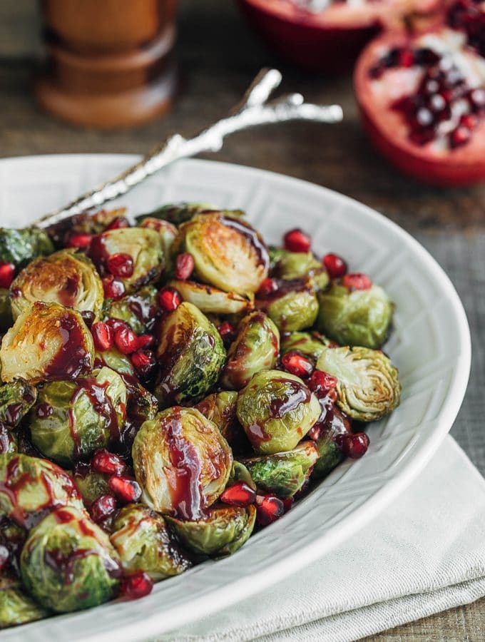 roasted brussels sprouts with pomegranate in a white serving dish
