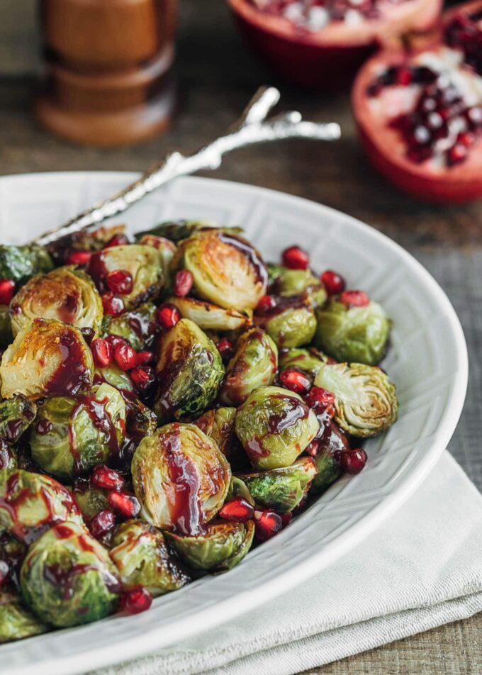 roasted brussels sprouts with pomegranate in a white serving dish