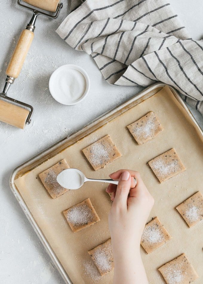  saupoudrer de sucre sur des biscuits sablés chai non cuits sur une plaque à pâtisserie