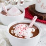 mugs of peppermint hot chocolate with whipped cream and candy cane sticks