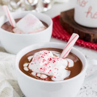 tazas de menta chocolate caliente con crema batida y un bastón de caramelo palos