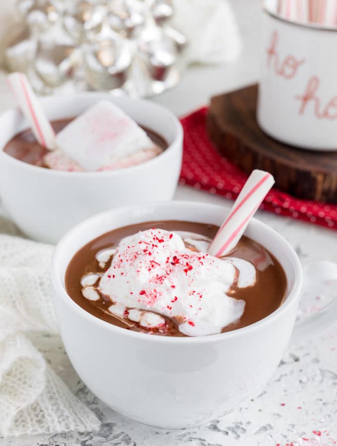 mugs of peppermint hot chocolate with whipped cream and candy cane sticks