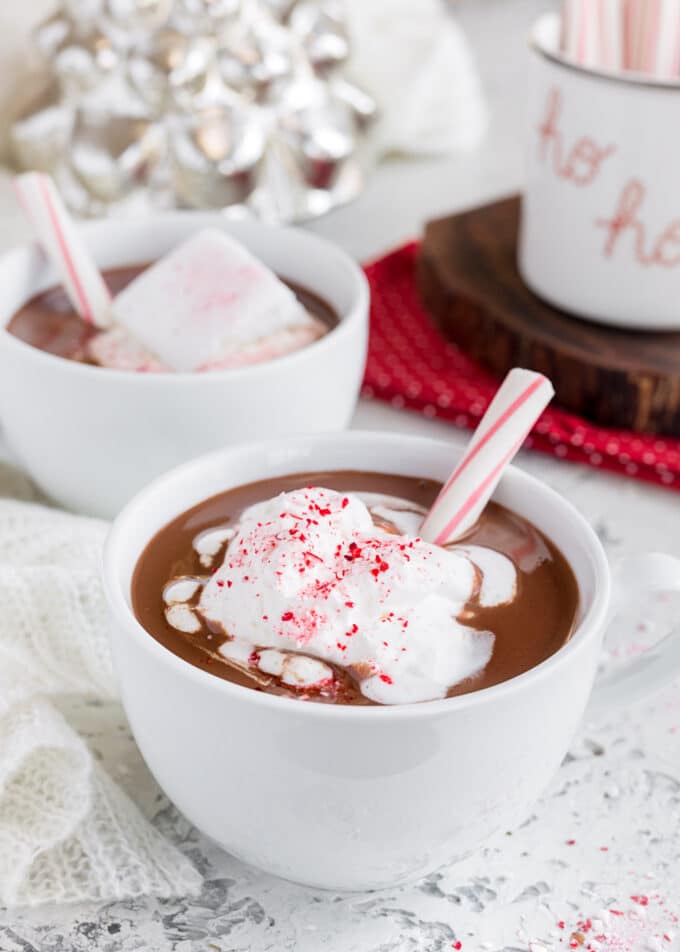 mugs of peppermint hot chocolate with whipped cream and candy cane sticks