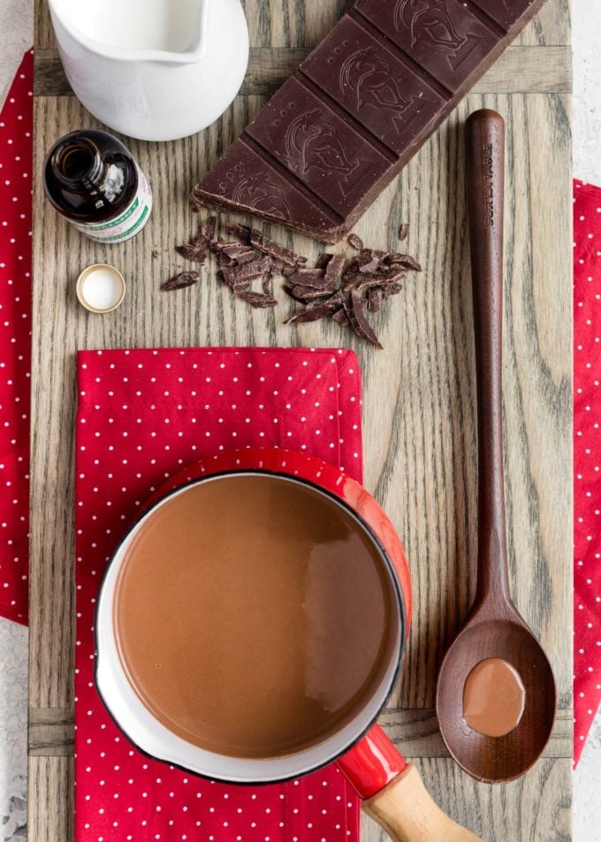 olla de menta chocolate caliente en una junta con un bloque de chocolate semidulce y una jarra de leche