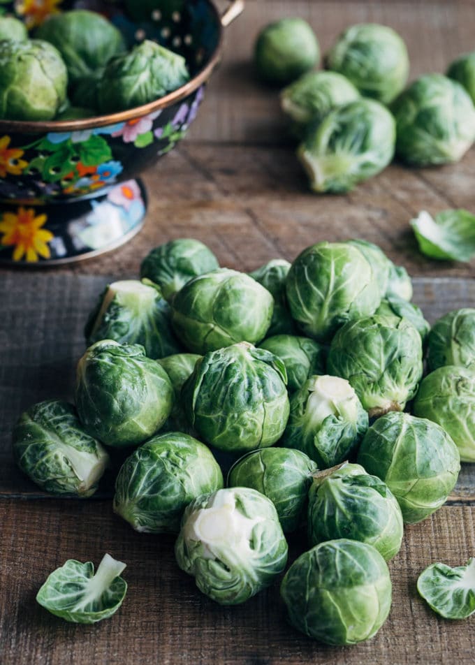 raw brussels sprouts on a wood board with a colander