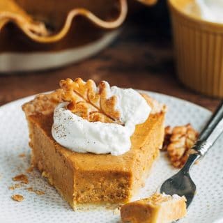 slice of pumpkin custard pie with whipped cream on a plate