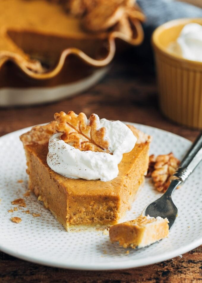 slice of pumpkin custard pie with whipped cream on a plate