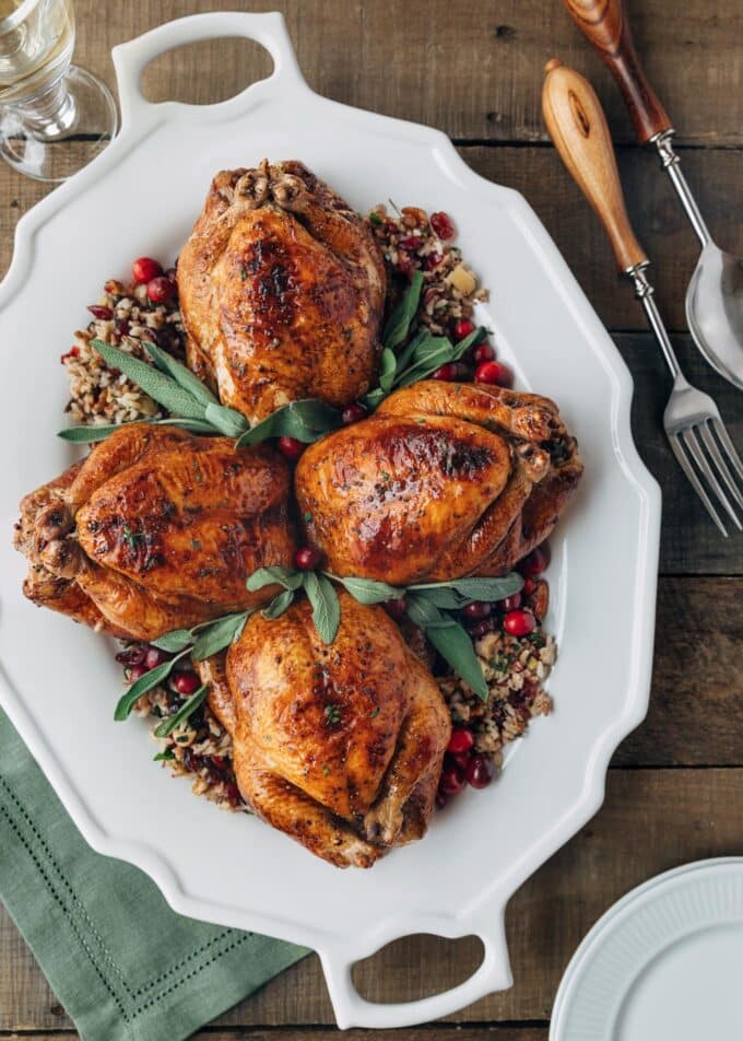 stuffed cornish hens on a white platter with fresh sage