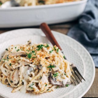 turkey tetrazzini on an ivory plate with a wood-handled fork