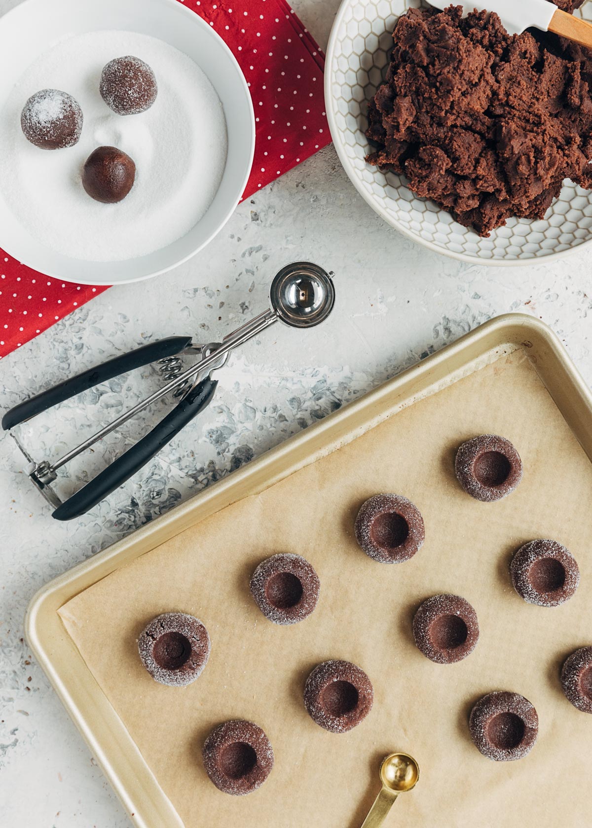 chocolate thumbprint cookie dough scooped onto a baking sheet