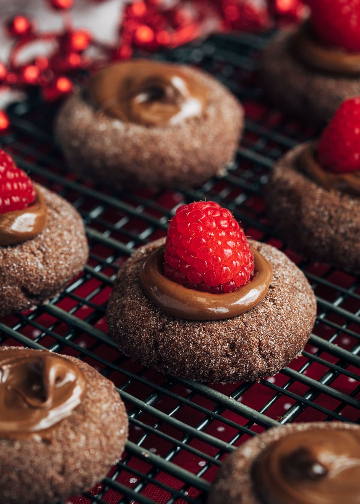 closeup of a chocolate hazelnut thumbprint cookie with a raspberry on top