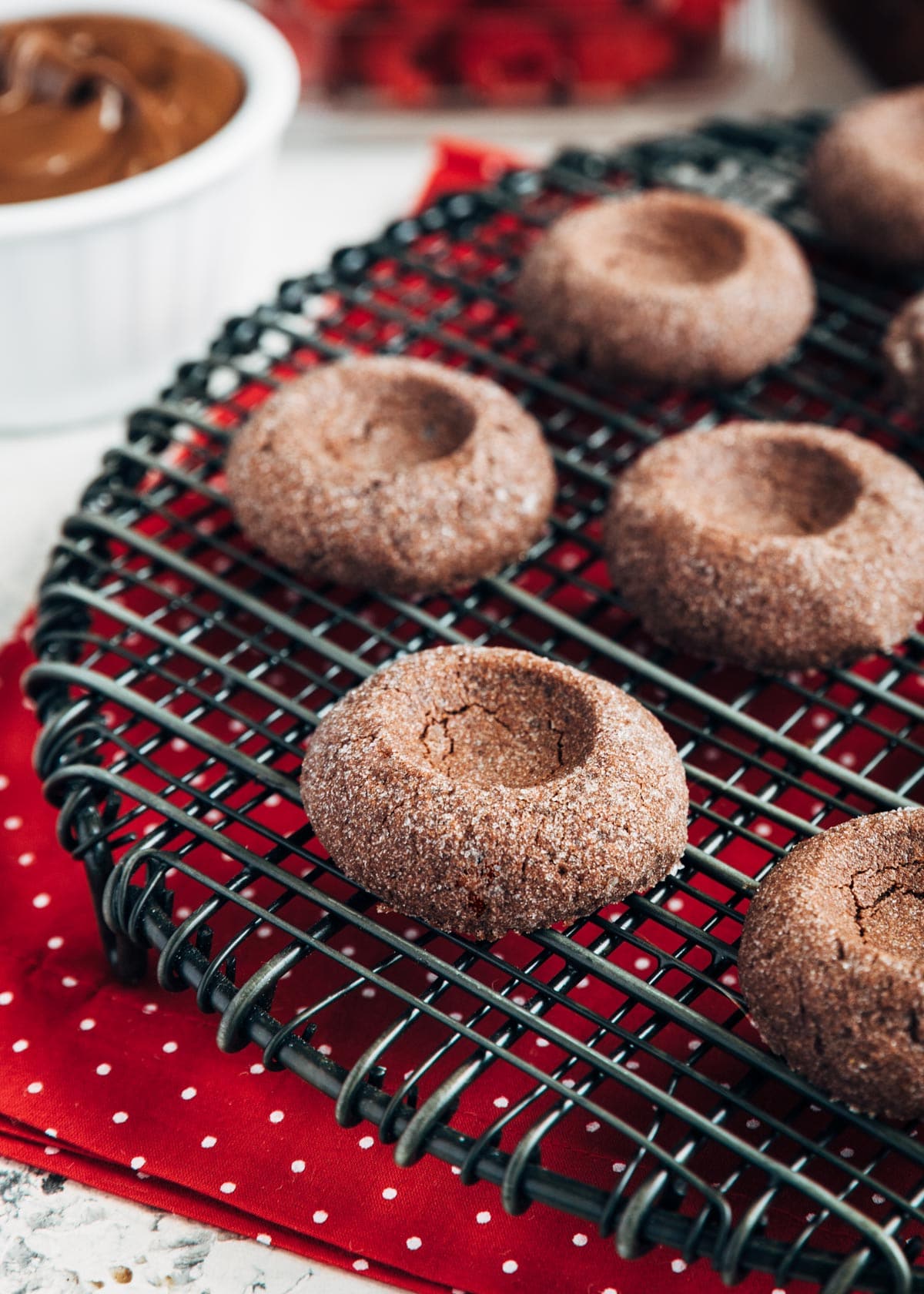 unfilled baked chocolate thumbprints on a black wire cooling rack 