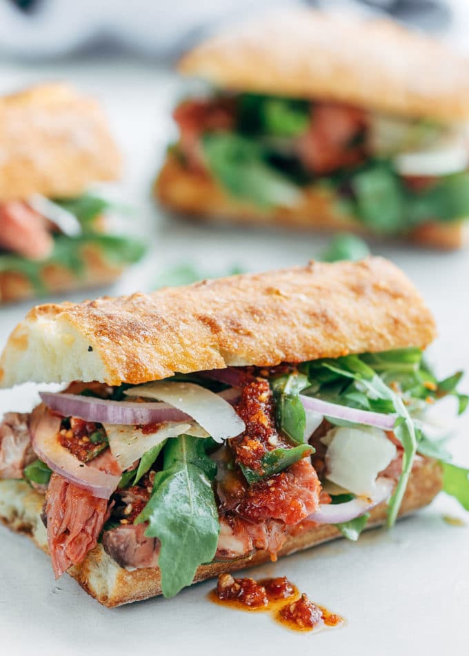 prime rib sandwich with pesto rosso, shaved asiago, and arugula on a ciabatta roll