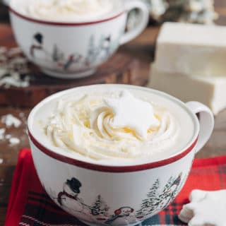 white hot chocolate in large mugs with whipped cream and snowflake shaped marshmallows