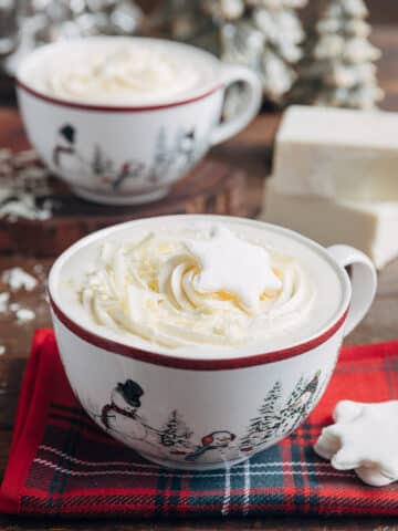 white hot chocolate in large mugs with whipped cream and snowflake shaped marshmallows