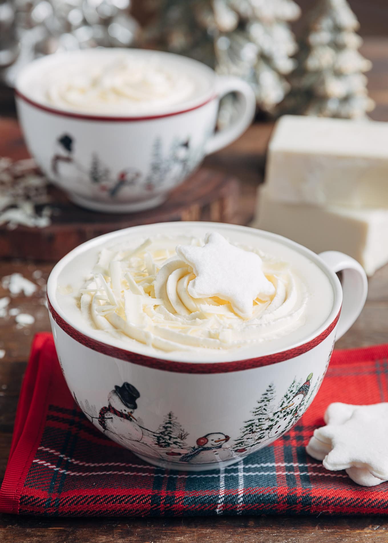 white hot chocolate in large mugs with whipped cream and snowflake shaped marshmallows