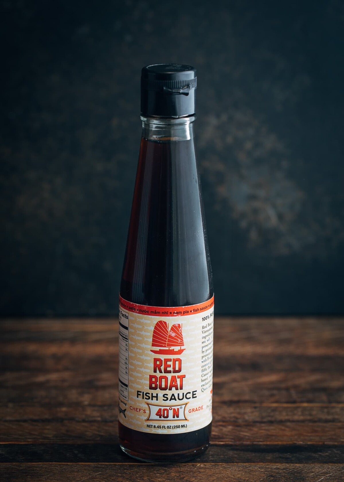 bottle of red boat fish sauce on a wood board with a black background