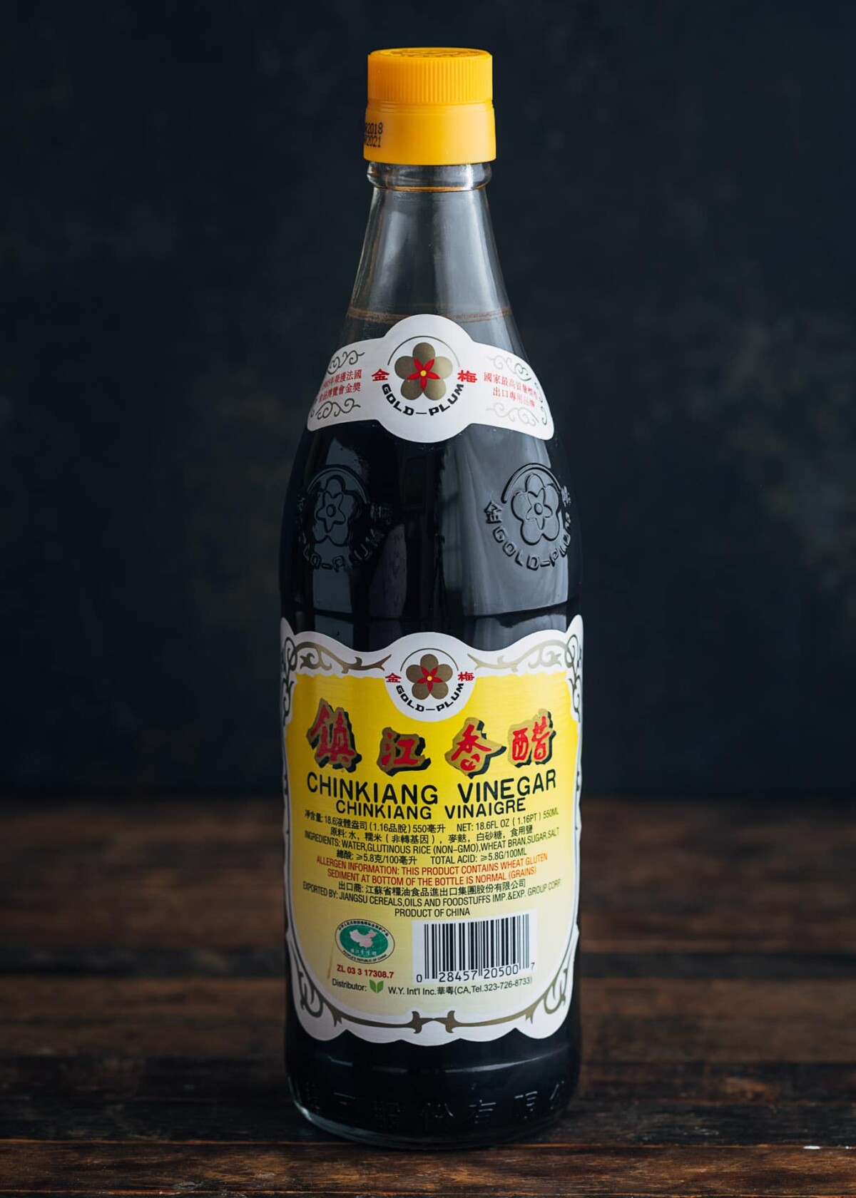 bottle of Chinkiang vinegar (Chinese black vinegar) on a wood board with a black background