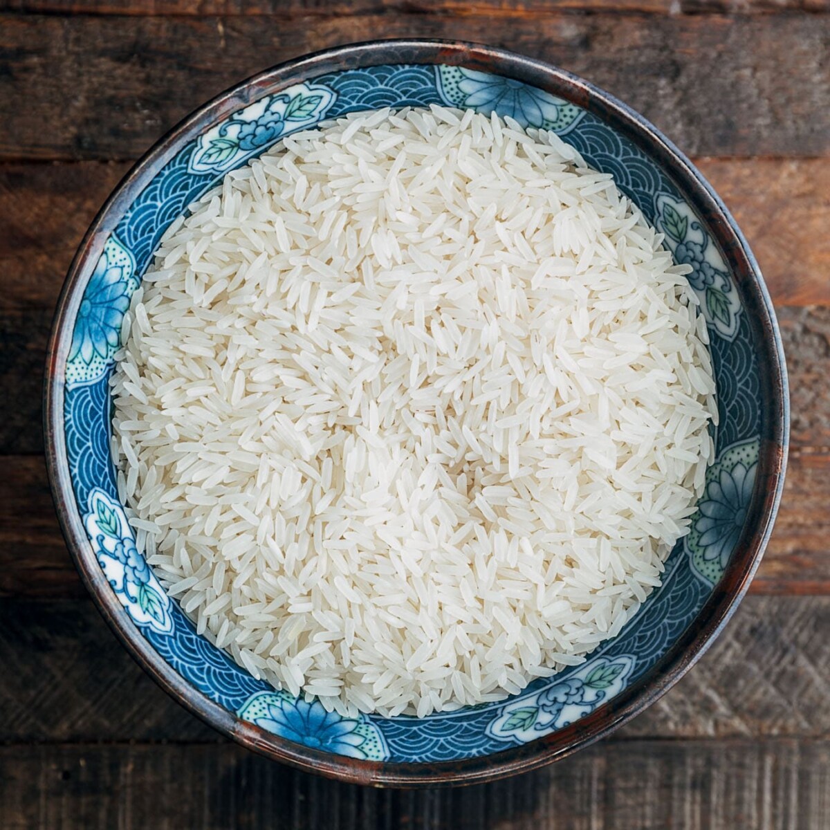 uncooked jasmine rice in a bowl on a wood board