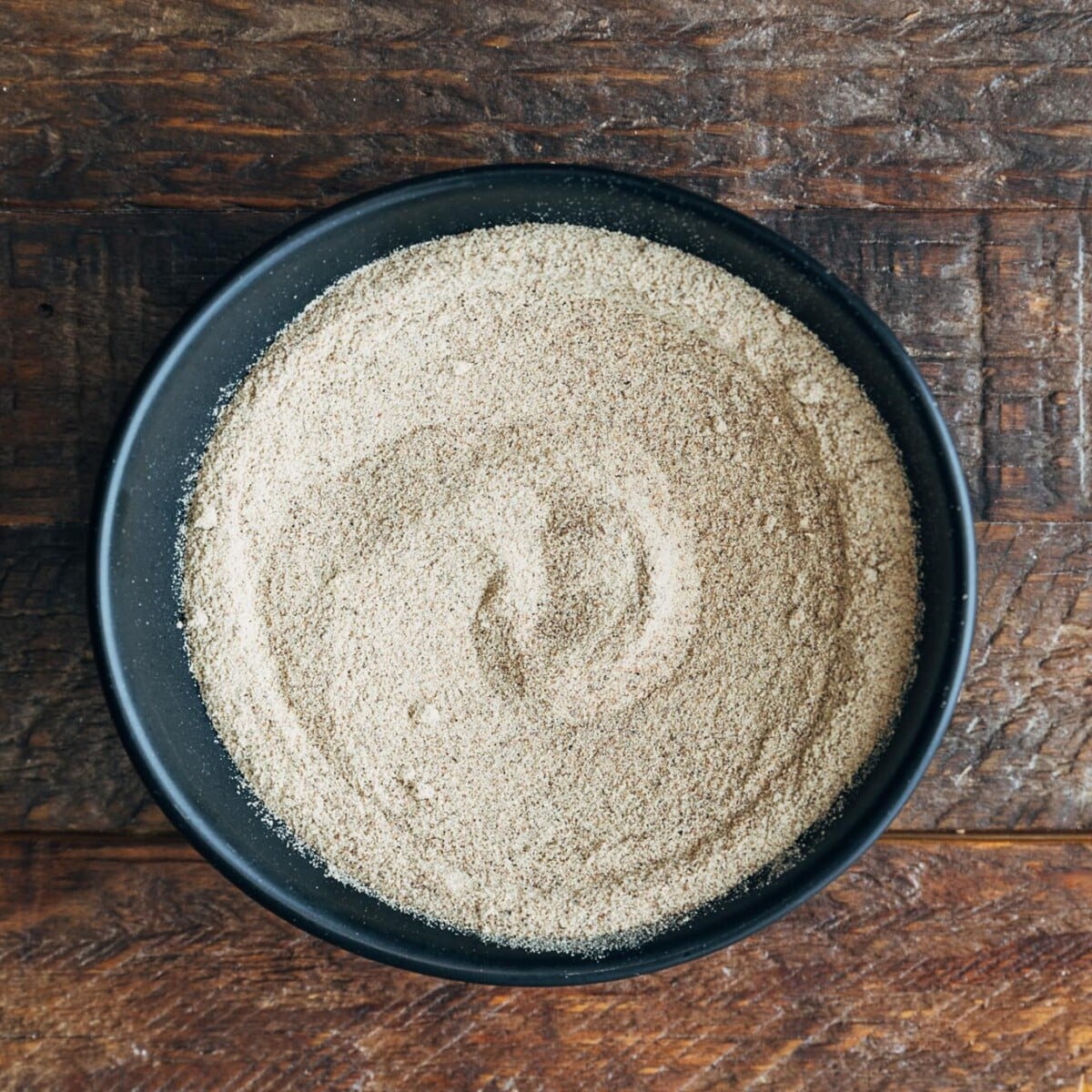 ground white pepper in a bowl in a wood board
