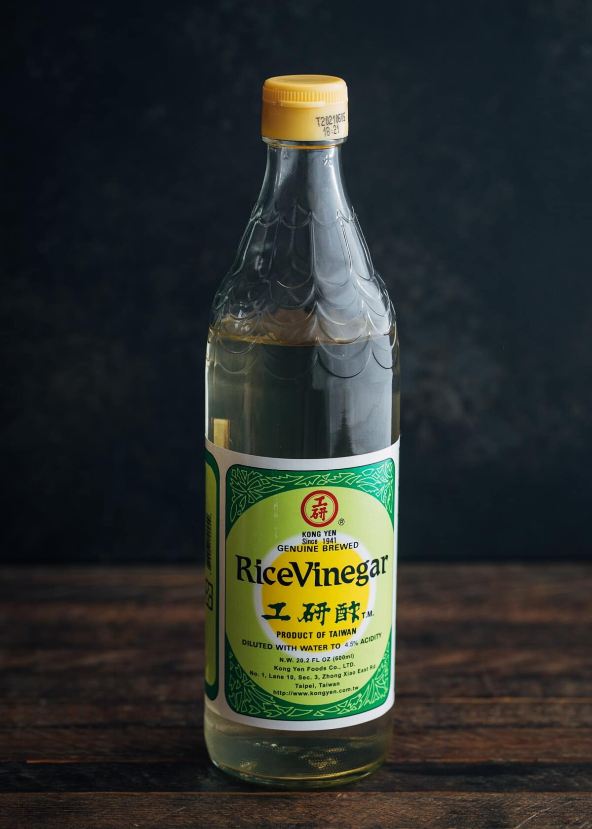 bottle of rice vinegar on a wood board with a black background