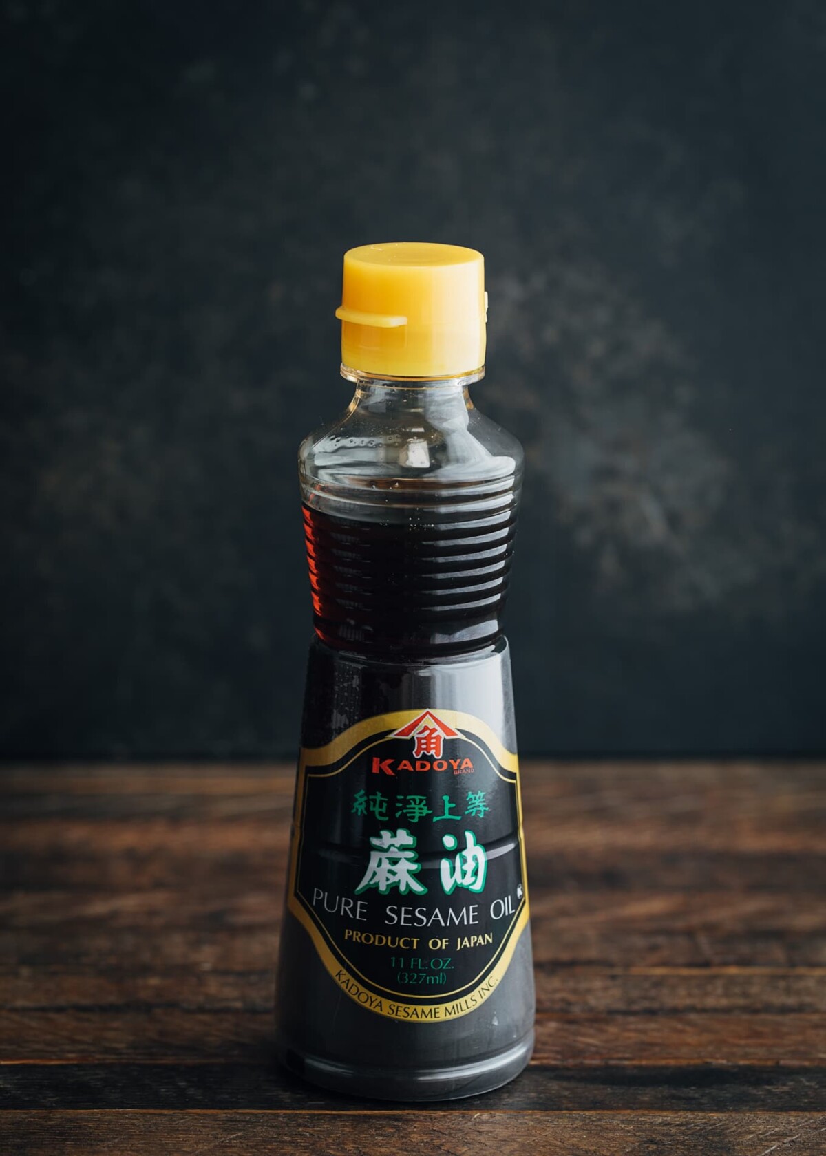 bottle of Japanese pure sesame oil on a wood board with a black background