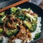 chinese beef and broccoli with rice in a black bowl