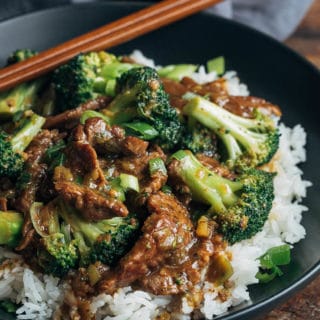 chinese beef and broccoli with rice in a black bowl