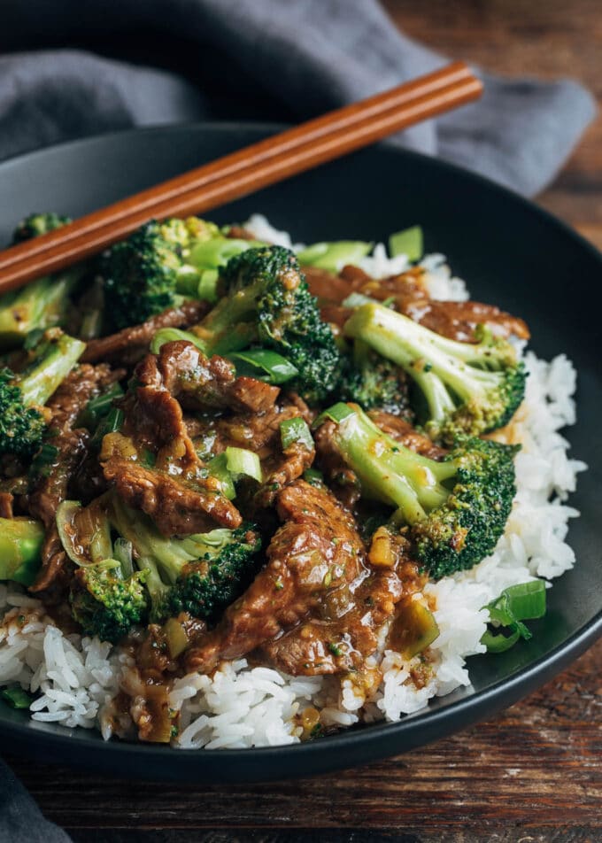 chinese beef and broccoli with rice in a black bowl