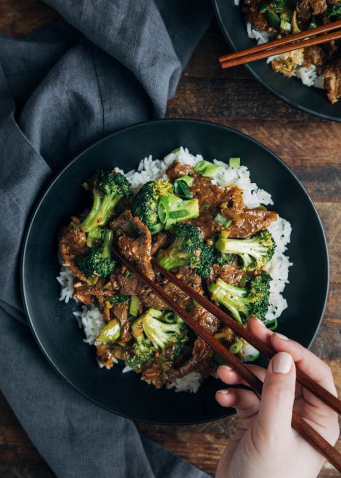 overhead of Beef and Broccoli over rice being eaten with chopsticks