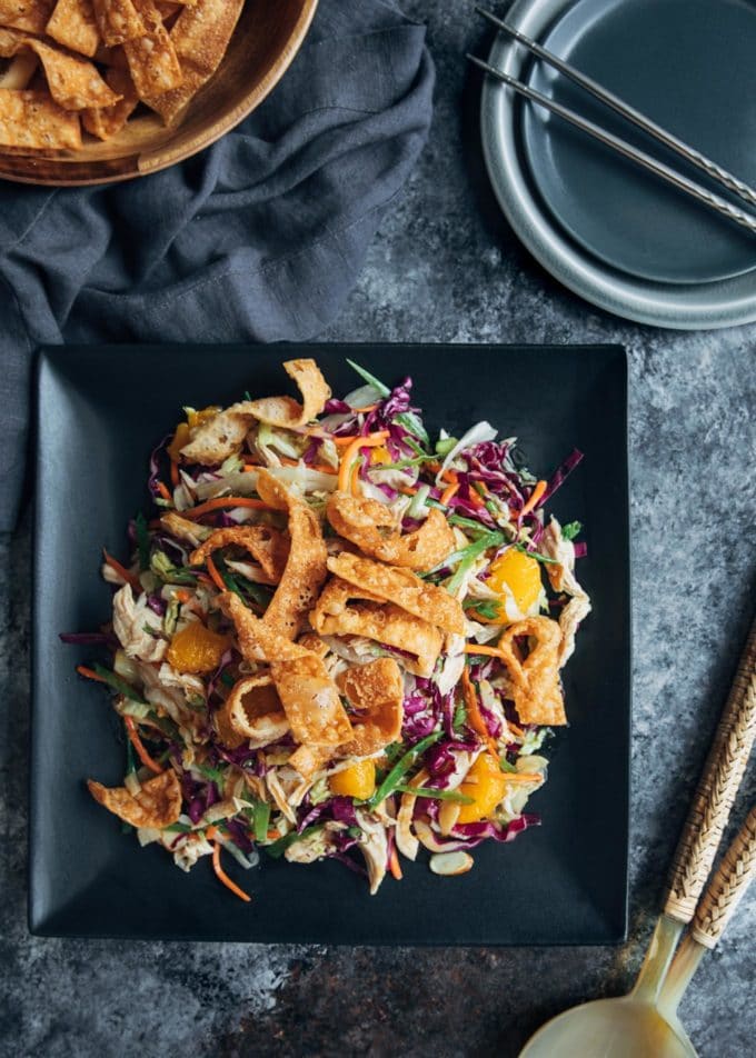 overhead of mandarin orange chicken salad served on a black plate with fried wonton strips