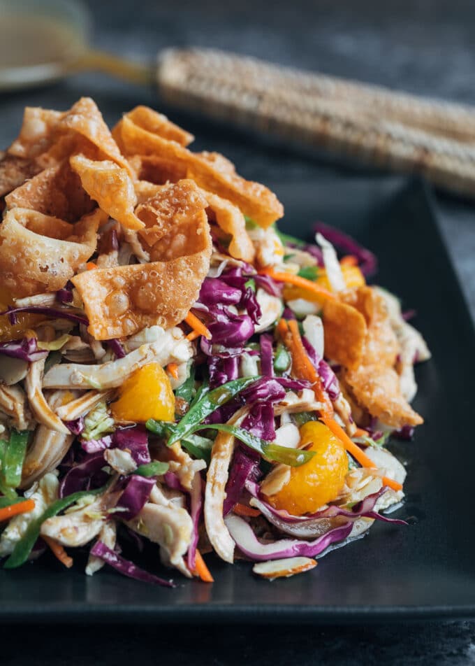 mandarin orange chicken salad with crispy wonton strips on a black plate 