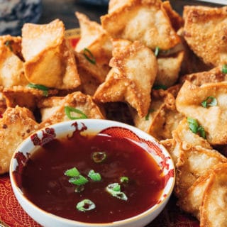 deep fried crab rangoon puffs on a plate with sweet and sour dipping sauce