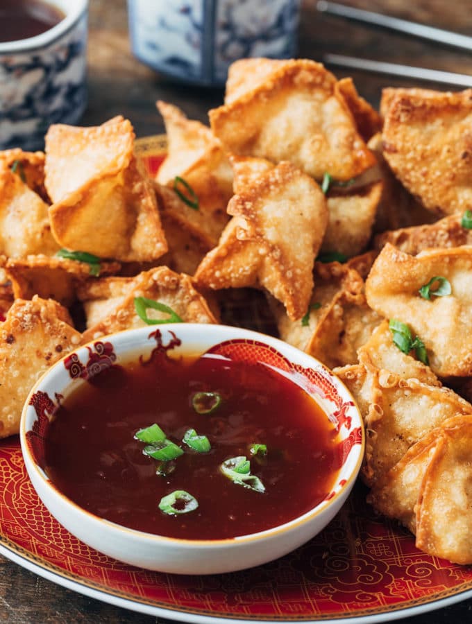 deep fried crab rangoon puffs on a plate with sweet and sour dipping sauce