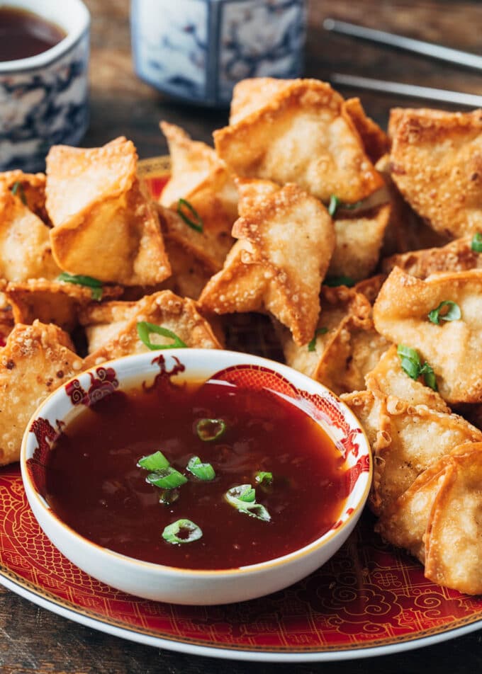 deep fried crab rangoon puffs on a plate with sweet and sour dipping sauce